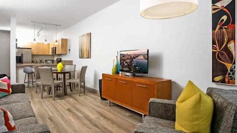 A living room with a grey couch, a yellow pillow, a wooden cabinet, and a painting on the wall.