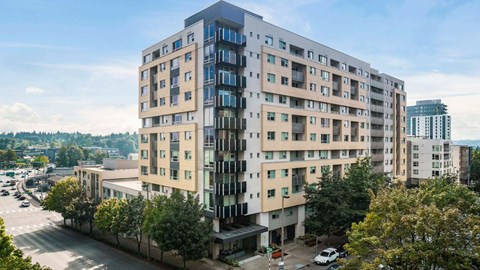 A large, modern apartment building with a mix of beige and blue balconies.