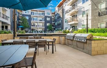A patio with tables and chairs is surrounded by apartment buildings.