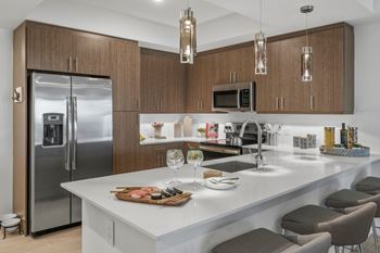 A modern kitchen with a white countertop and stainless steel appliances.