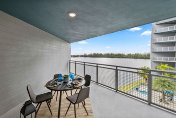A balcony with a table and chairs overlooking a pool.