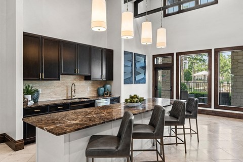 a kitchen with black cabinets and a counter with chairs
