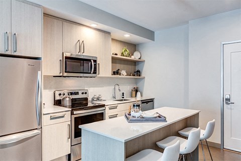 a kitchen with stainless steel appliances and a counter with chairs