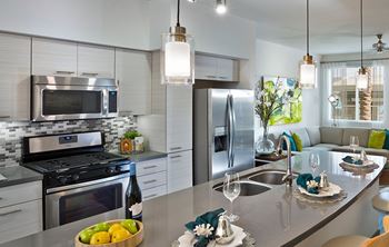 A modern kitchen with a stainless steel refrigerator, microwave, and oven.