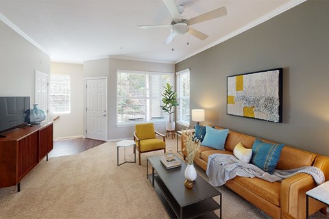 A living room with a brown couch, a yellow chair, and a painting on the wall.
