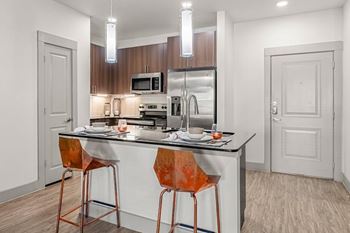 A kitchen with a white countertop and orange barstools.