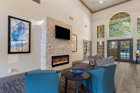 A living room with a stone fireplace and a television above it.