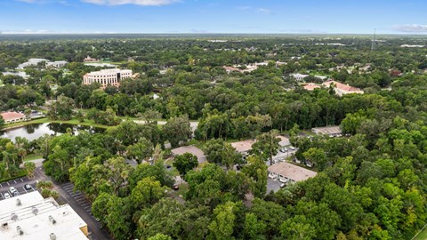 A bird's eye view of a green campus with a large building in the distance.