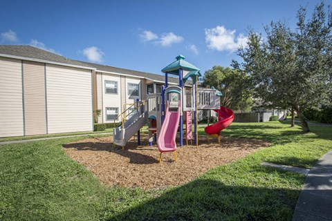 A playground with a slide and a red chair.