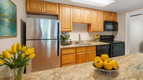 A kitchen with wooden cabinets and a stainless steel refrigerator.