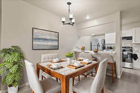 A dining room with a wooden table set for two with a view of the ocean.