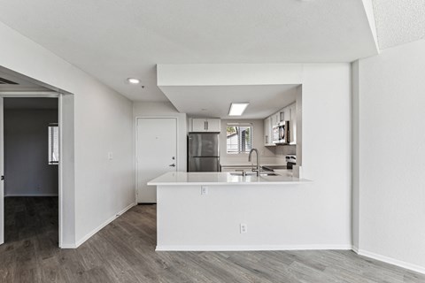 an open kitchen and living room with white walls and wood flooring