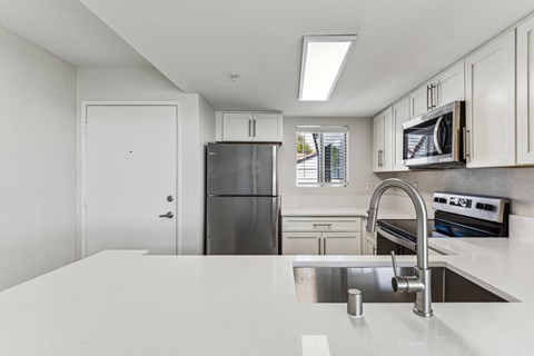 a white kitchen with stainless steel appliances and a white counter top
