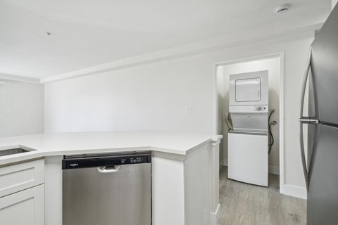 a white kitchen with stainless steel appliances and a white counter top