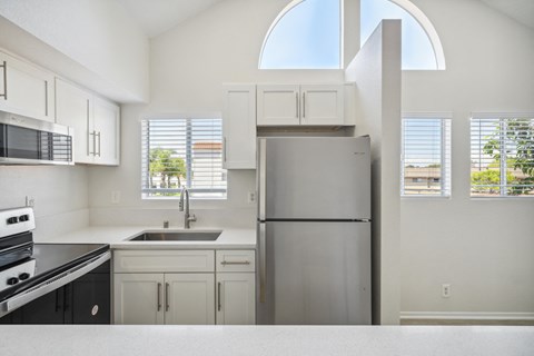 a white kitchen with a stainless steel refrigerator
