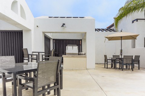 a patio with tables and chairs and an umbrella