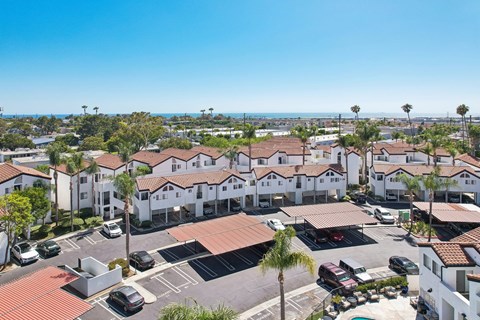 A sunny day at a residential complex with cars parked in the lot.