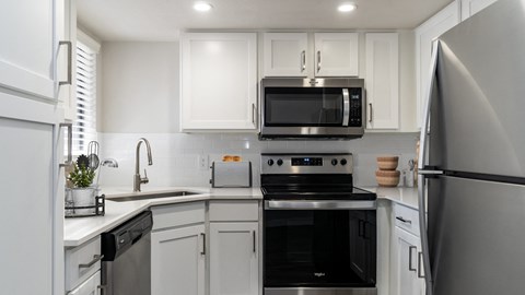 a kitchen with white cabinets and black appliances