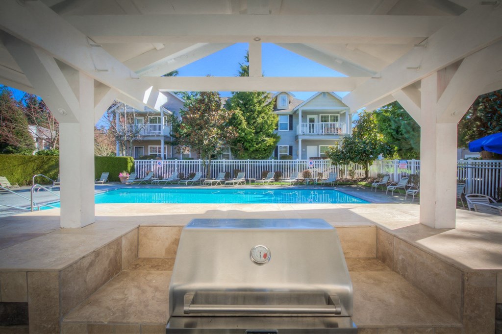 a swimming pool with a hot tub and a pool house in the background