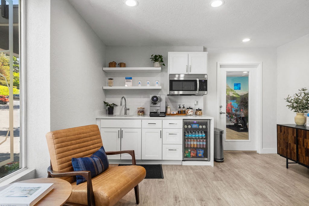 a living room with a chair and a kitchen with a microwave