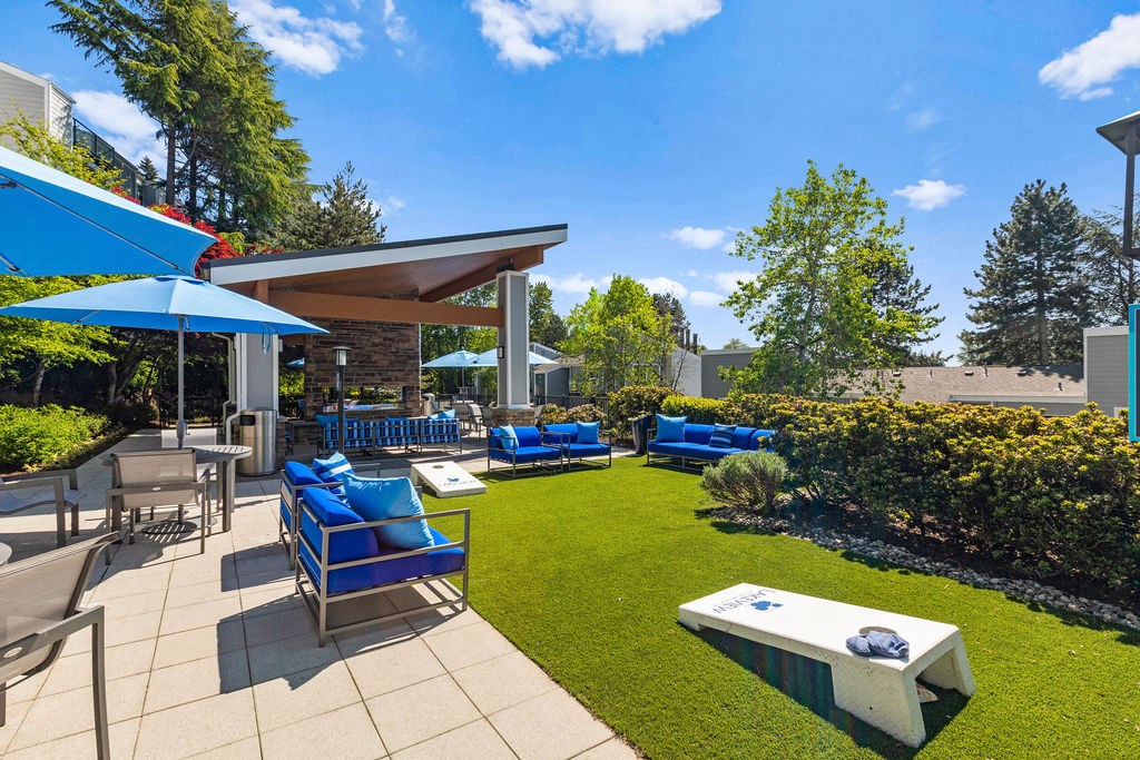 a patio with blue chairs and umbrellas and a lawn