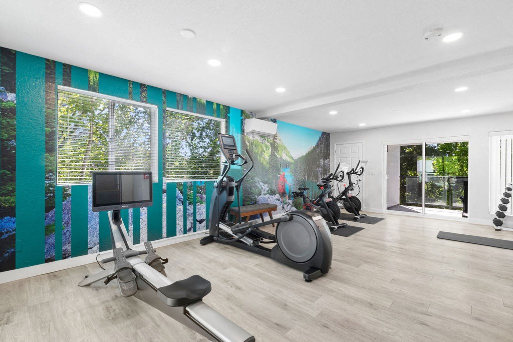 the gym has plenty of exercise equipment and a mural on the wall