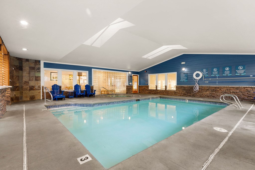 a swimming pool with blue chairs and a blue wall with a water feature