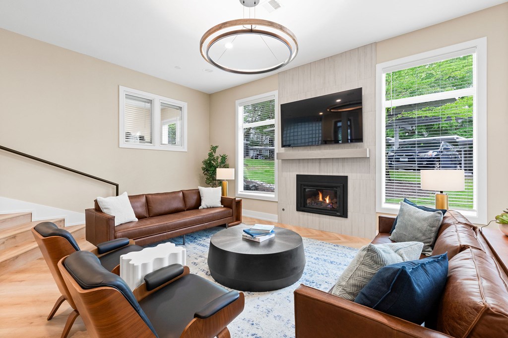 A living room with a brown leather couch, a fireplace, and a television.