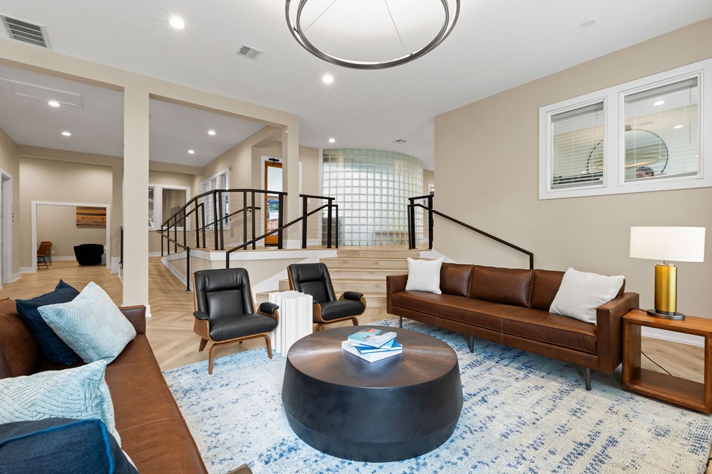 A living room with a brown couch, a blue rug, and a black coffee table.