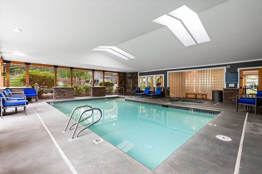A large indoor swimming pool with a diving board and lounge chairs.