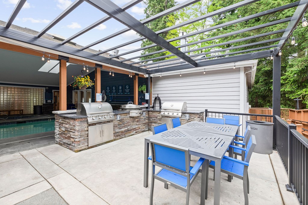 A patio with a table and chairs and a grill.