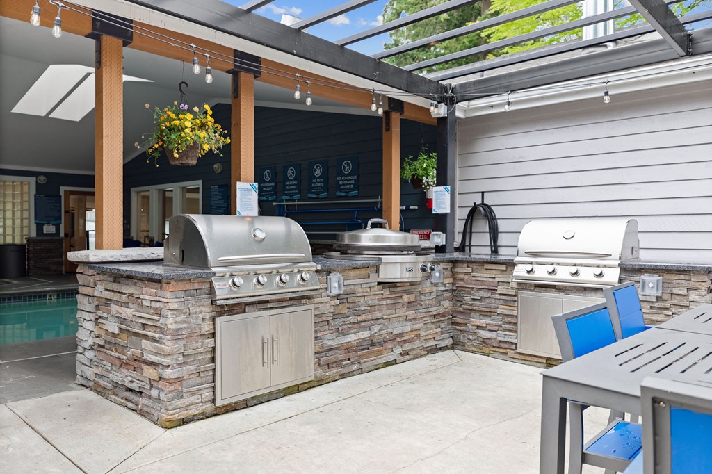 A patio with a stone barbecue and a table.