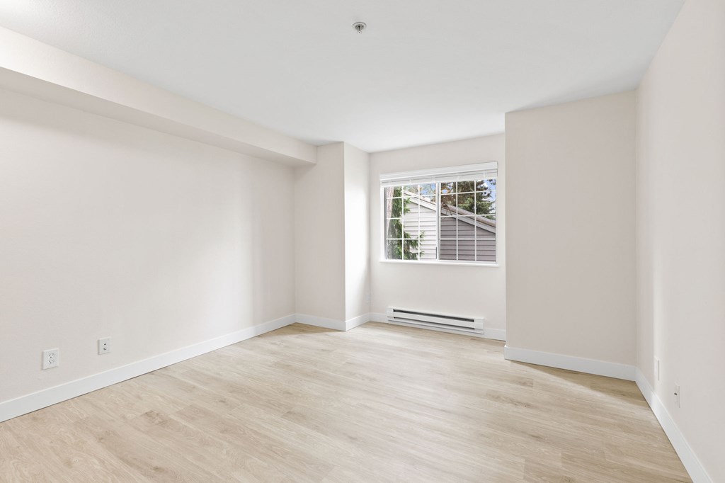 A room with a window and a wooden floor.