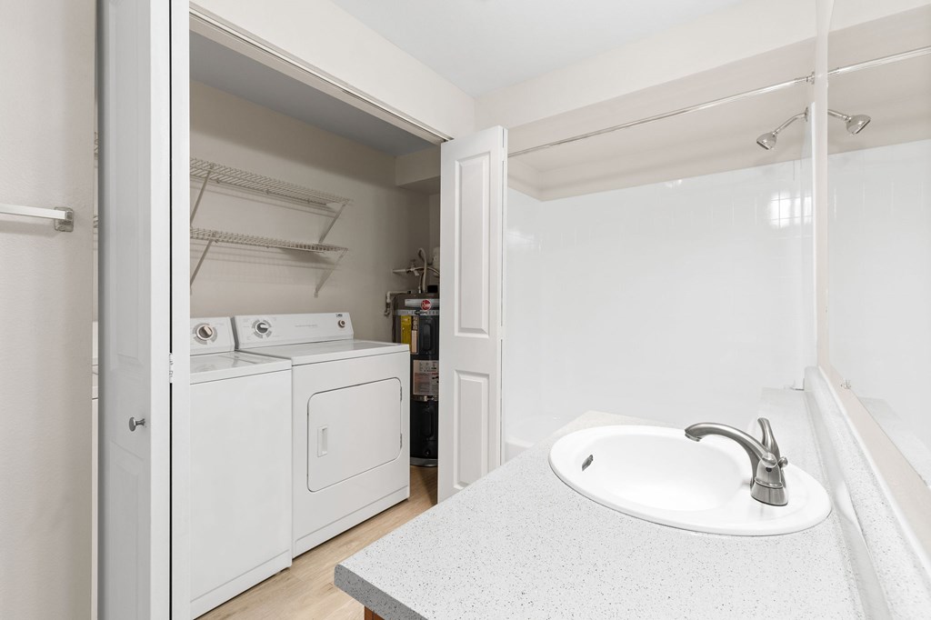 A white bathroom with a sink and a washer and dryer.