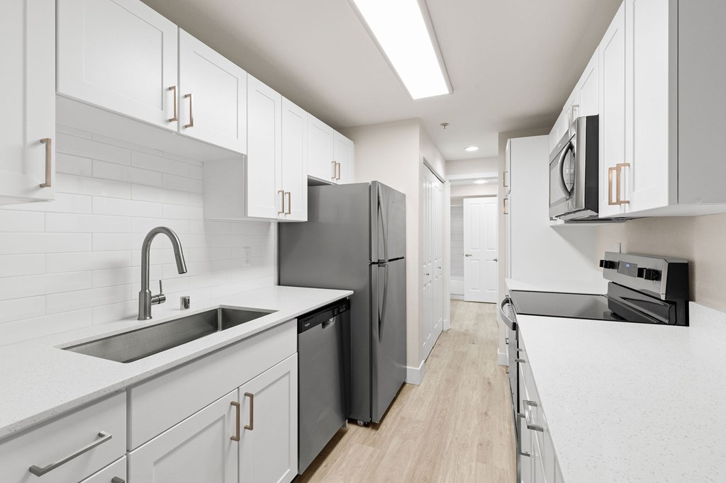 A modern kitchen with white cabinets and a black fridge.