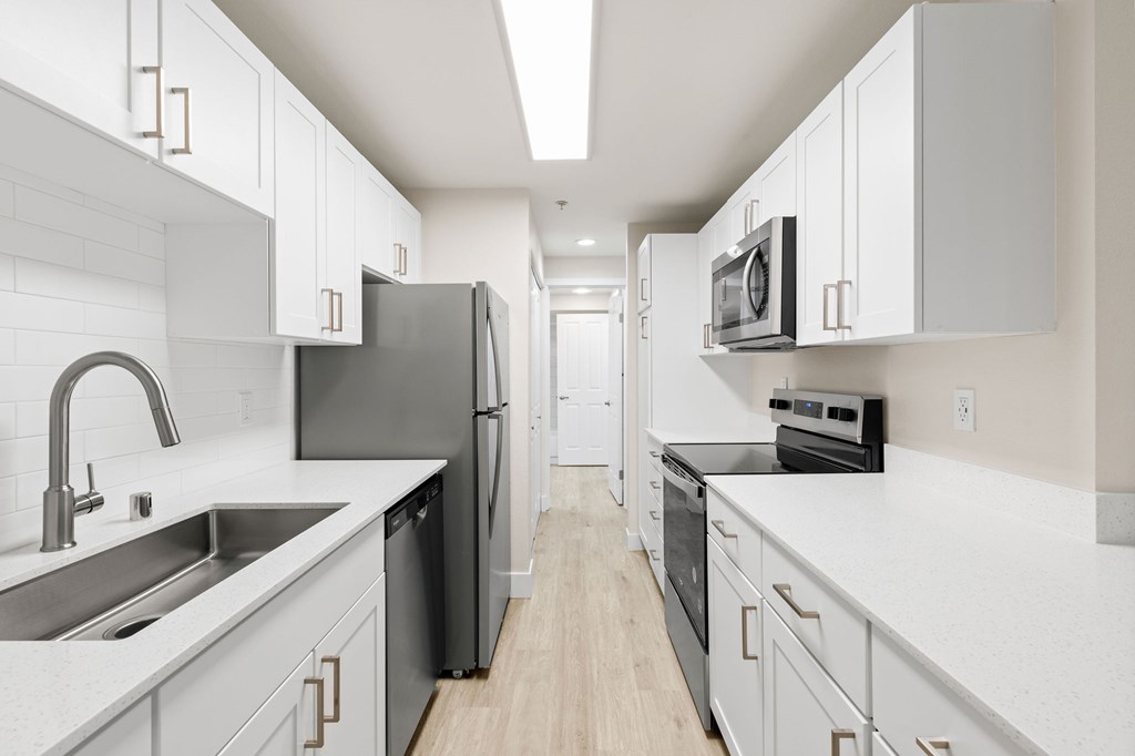 A modern kitchen with white cabinets and black appliances.