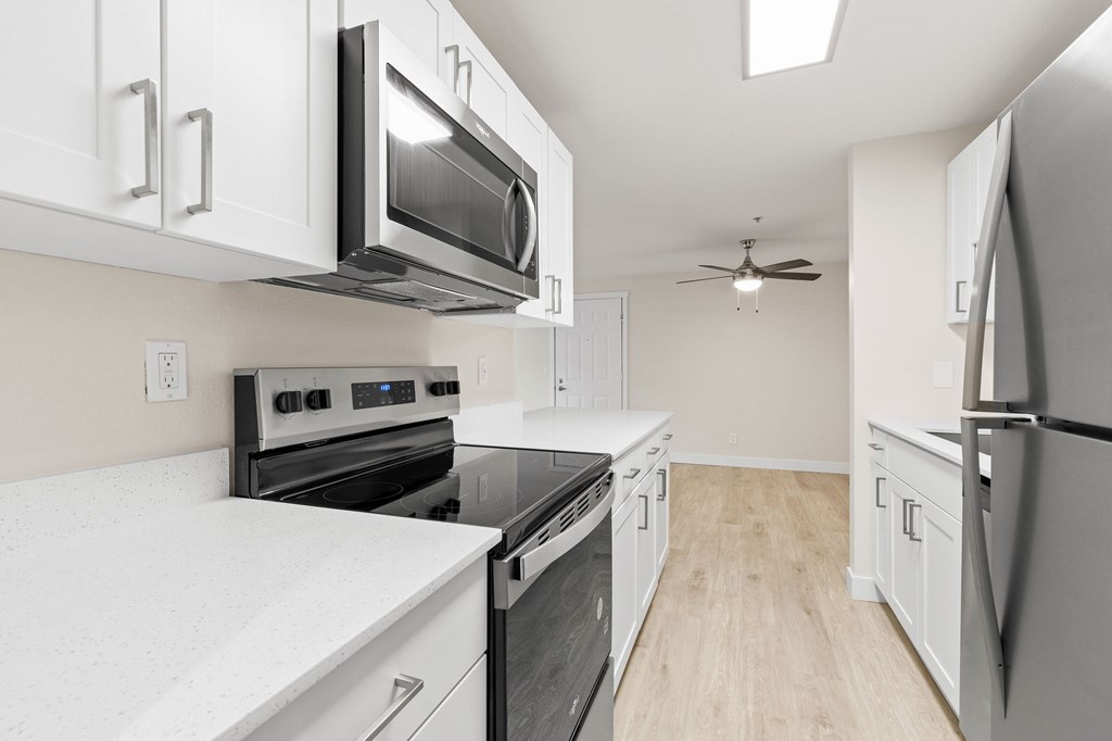 A kitchen with white cabinets and black appliances.