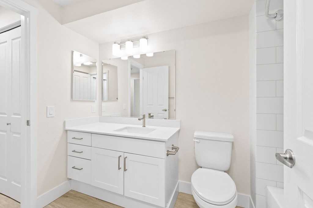 A white bathroom with a toilet, sink, and mirror.