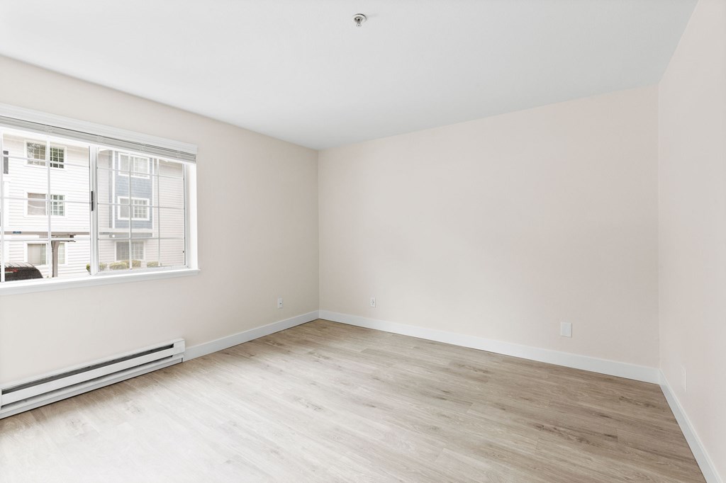 Empty room with a window and a radiator on the wall.