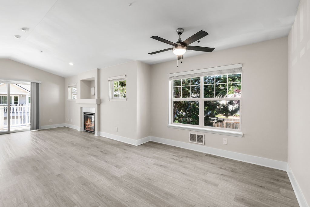 A spacious living room with a fireplace and a ceiling fan.