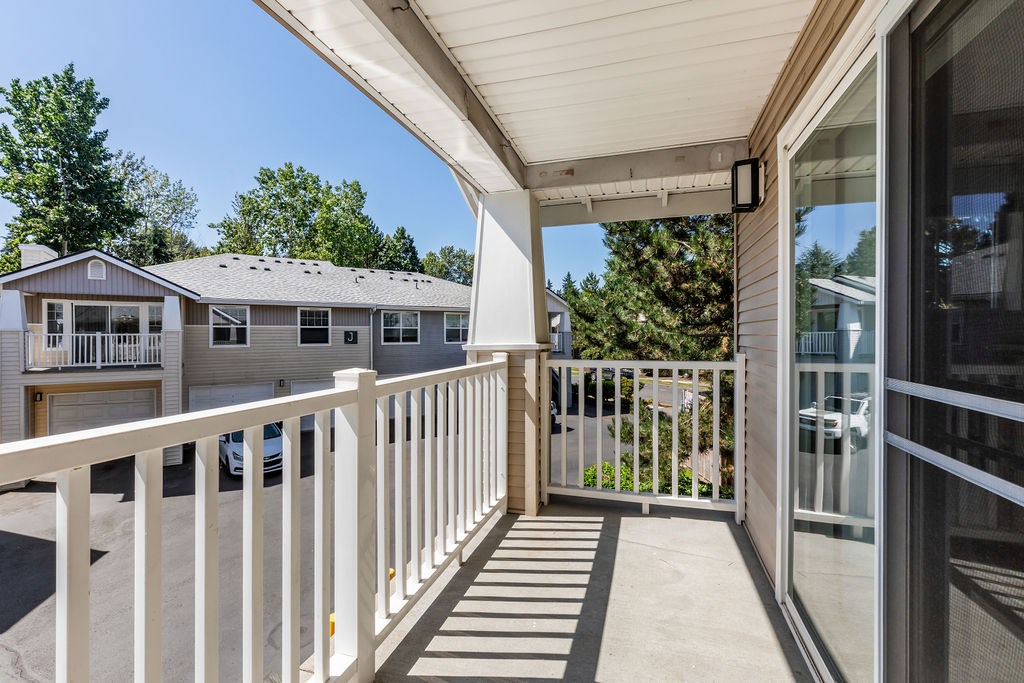 A white balcony with a glass door and a white railing.