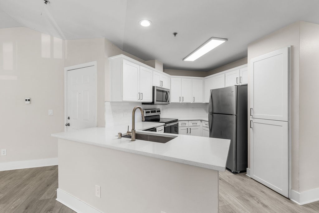 A kitchen with white cabinets and a black refrigerator.