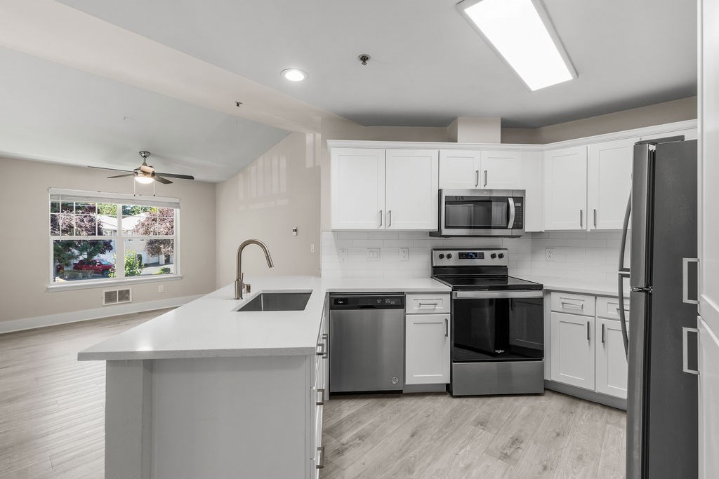 A modern kitchen with stainless steel appliances and white cabinets.