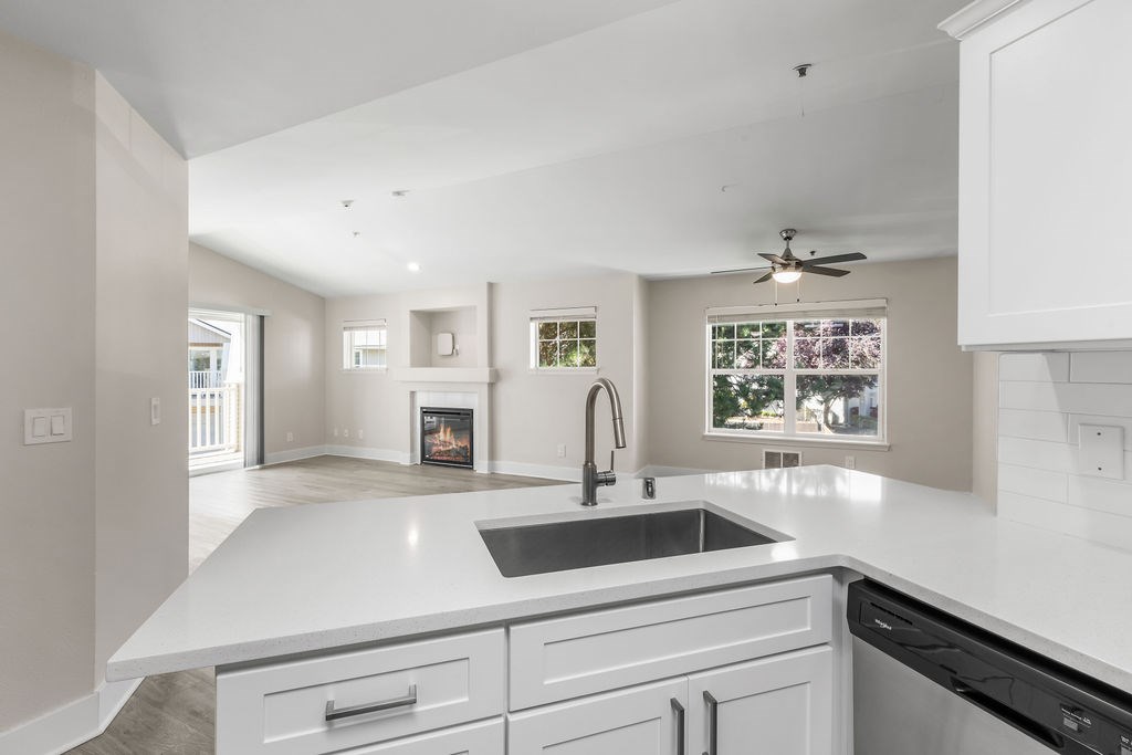 A modern kitchen with a white countertop and a fireplace in the background.
