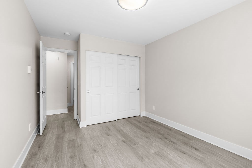 A white door is in the middle of a room with wood flooring.