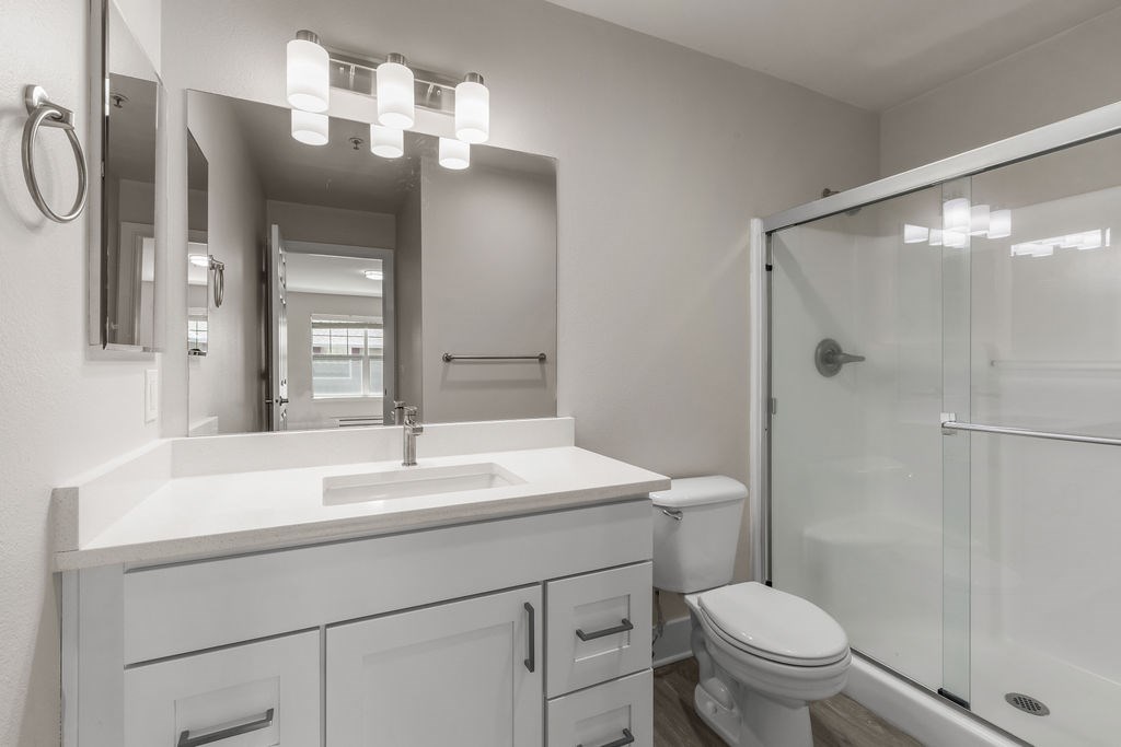 A white bathroom with a sink, toilet, and mirror.