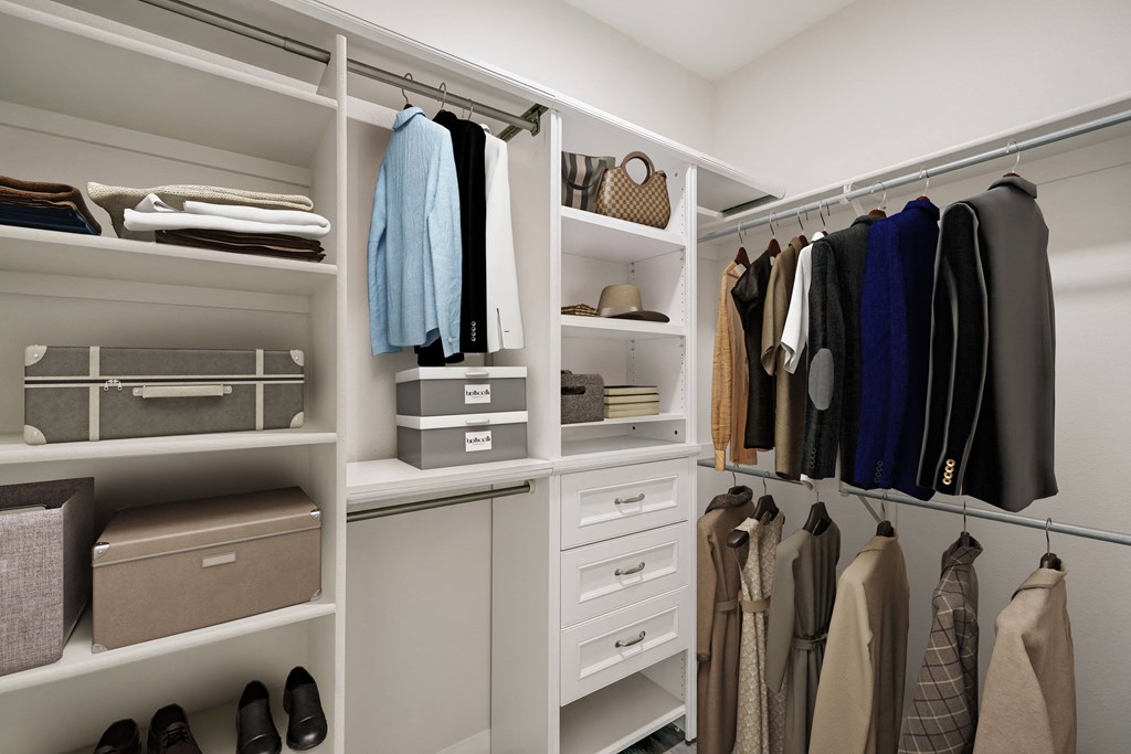 a walk in closet with white cabinets and shelves and a closet organizer