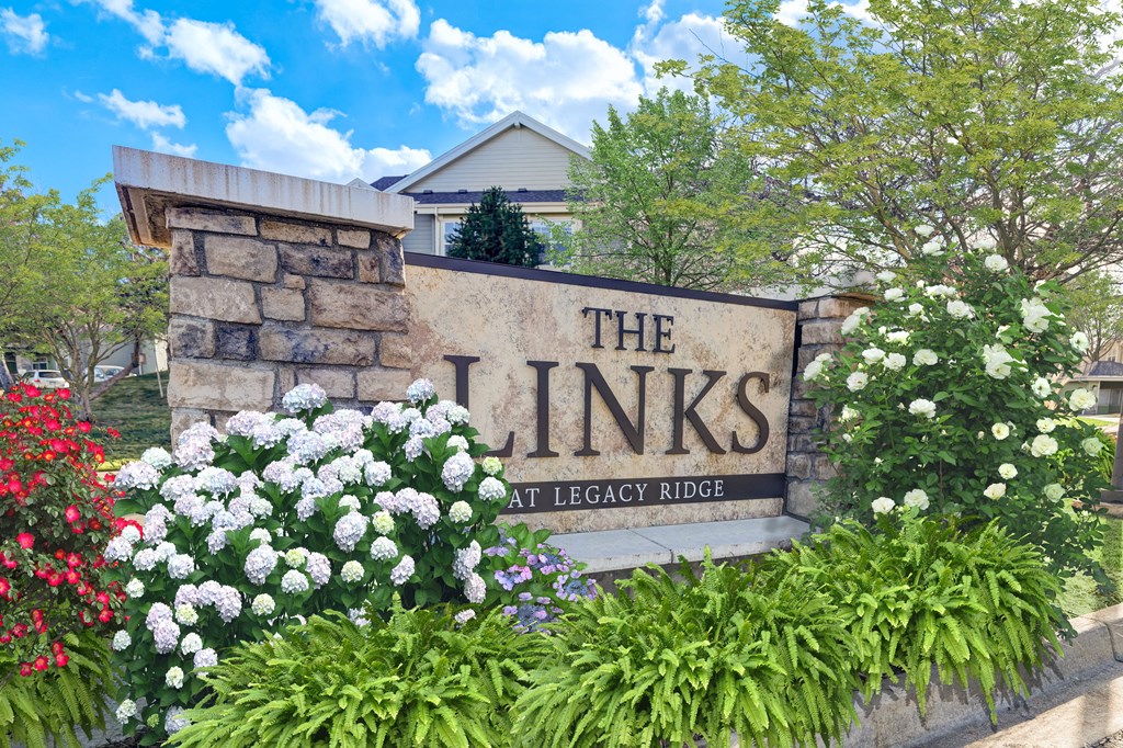 a sign for the links at legacy ridge with flowers around it