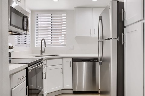 A modern kitchen with white cabinets and stainless steel appliances.
