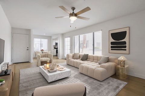 A modern living room with a large sectional sofa, a coffee table, and a ceiling fan.